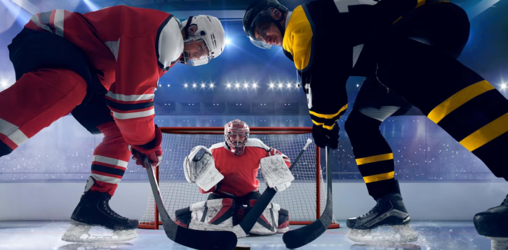 three players with  hockey sticks near the goalkeeper